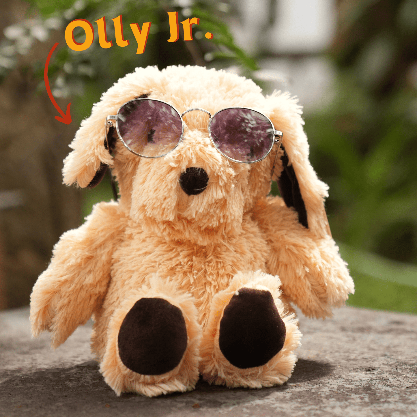 Olly Jr plush dog by SOUL wearing round sunglasses sitting outdoors on stone surface