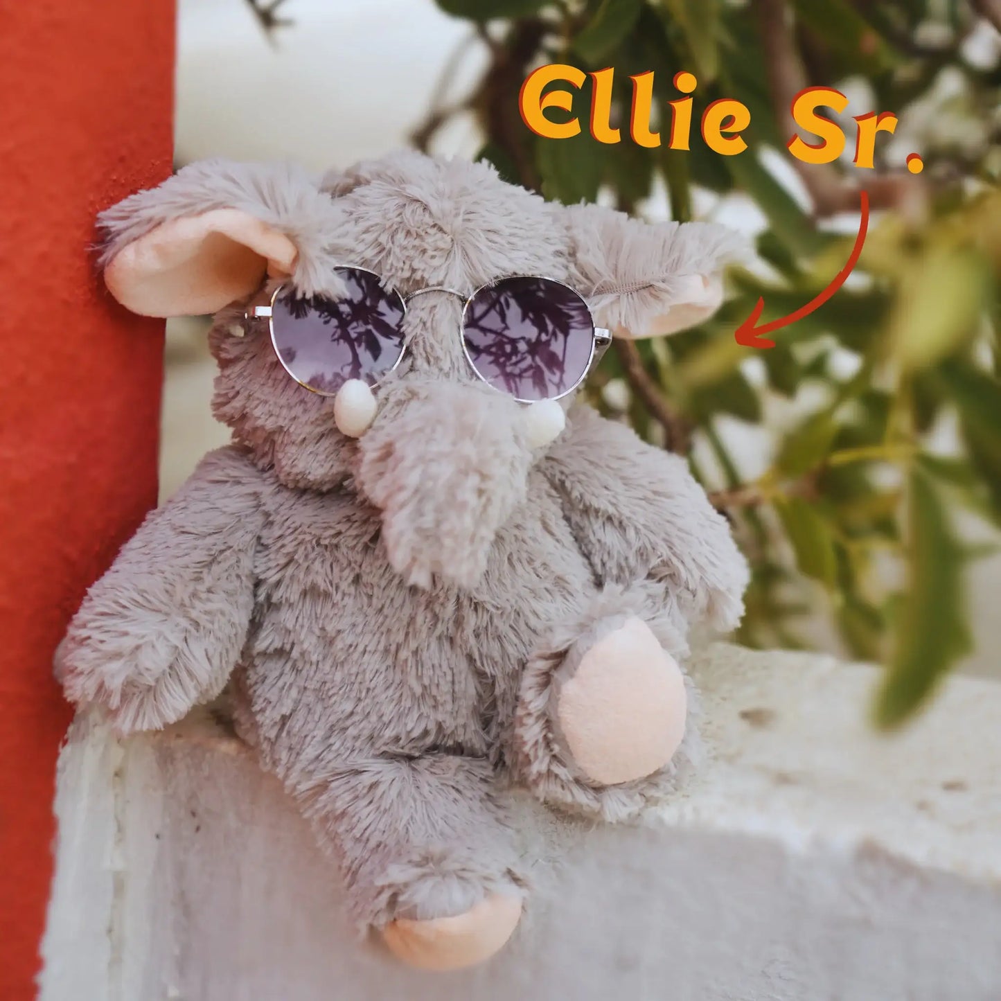 Ellie Sr. microwavable comfort plush elephant wearing sunglasses sitting outdoors by SOUL